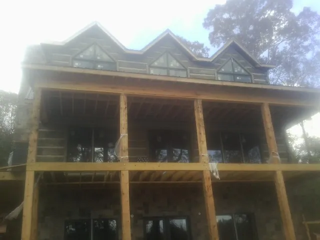 Dormers and porch framing on a large log home under construction — Roof Coating work by our crew in Lynnville